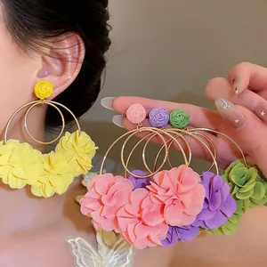 Dettaglio macro di orecchini a cerchio con fiori in chiffon colorati stile boho