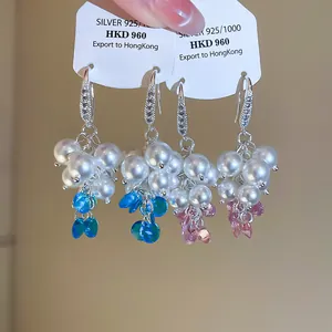 Dettaglio di orecchini a perla a forma di uva con cristalli scintillanti e ganci in argento.