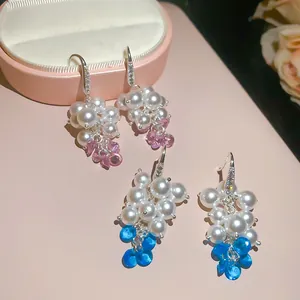 Primo piano di graziosi orecchini di perle a uva con dettagli in zircone blu e rosa.