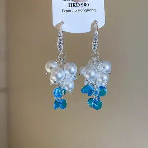 Dettaglio di eleganti orecchini a grappolo d'uva con perle bianche e perline blu