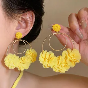 Vista ravvicinata dettagliata degli orecchini a cerchio con fiori di chiffon gialli su modella