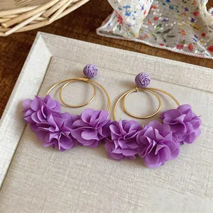 Dettaglio orecchini a cerchio con fiori in chiffon viola e metallo dorato in stile vacanza