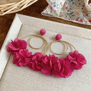 Dettaglio degli orecchini a fiori in chiffon magenta con cerchi dorati e aghi in argento