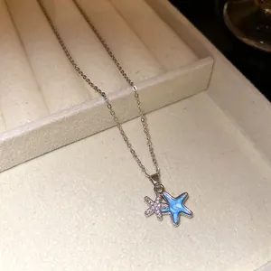 Nahaufnahme einer silbernen Halskette mit blauem Emaille- und Zirkon-Seestern-Anhänger.