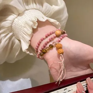 Close-up of an elegant multi-layered beaded bracelet with pink stones and tassels on a wrist