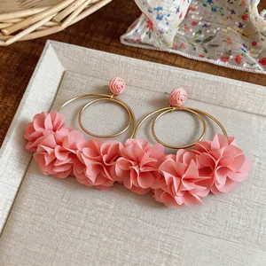 Dettaglio di eleganti orecchini a cerchio con fiori in chiffon rosa su vassoio chiaro