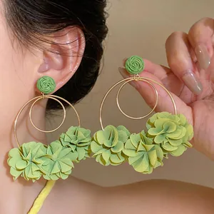 Dettaglio di orecchini a cerchio con fiori in chiffon verde dallo stile elegante da vacanza