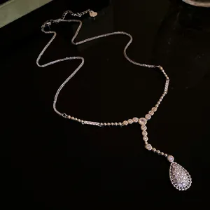 Elegante silberfarbene Halskette mit Zirkonia-Tropfenanhänger auf schwarzer Fläche