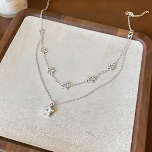 Close-up detail of a double-layer silver necklace with elegant zircon star charms.