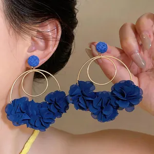 Dettaglio di grandi orecchini a cerchio con fiori di chiffon blu e anelli d'oro