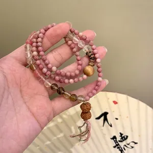 Macro detail of multilayered beaded bracelet with pink rhodonite and tiger eye stones.