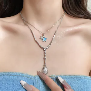Detail einer mehrlagigen silbernen Halskette mit blauem Emaille Stern und Zirkon Anhängern
