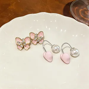 Macro detail view of elegant pink enamel butterfly and heart earrings with pearls and crystals