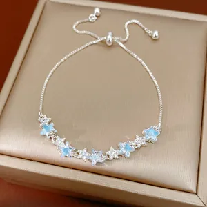 Detailed view of adjustable silver star bracelet with blue zircons on a gold jewelry box