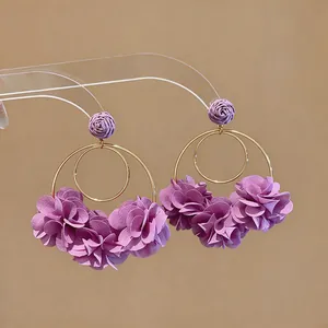Dettaglio macro di eleganti orecchini a fiore in chiffon viola con doppio cerchio dorato