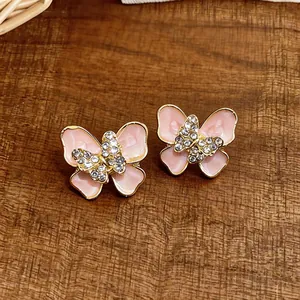 Close-up detail of pink enamel butterfly earrings with sparkling rhinestone accents.