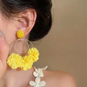 Primo piano di orecchini a cerchio con fiori in chiffon giallo e perno in raffia