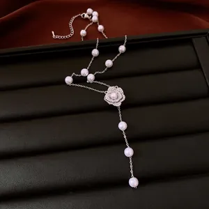 Detail of a vintage pearl beaded necklace with a crystal flower on a black tray.