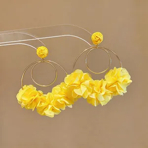 Dettaglio ravvicinato di orecchini a cerchio con fiori in chiffon giallo e petali