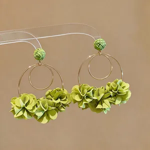 Primo piano di eleganti orecchini a cerchio con fiori in chiffon verde su base