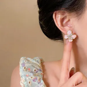 Close-up of elegant pink enamel flower stud earrings with rhinestone butterfly center