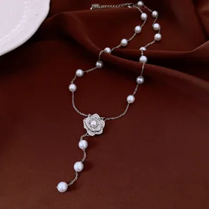 Elegant pearl necklace with zircon flower pendant on brown silk background texture.
