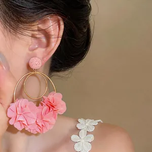 Dettaglio di eleganti orecchini a fiore in chiffon rosa indossati da una modella chic