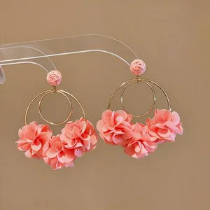 Primo piano di orecchini a cerchio con fiori in chiffon rosa per un look resort.