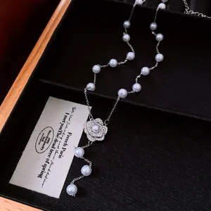 Detailed macro view of an elegant pearl necklace with a sparkling zircon flower pendant