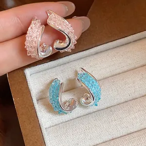 Close-up view of elegant irregular curved earrings with pink and blue crushed glass texture