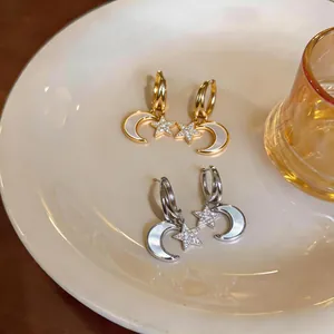 Détail des boucles d'oreilles étoiles et lunes en or et argent avec nacre