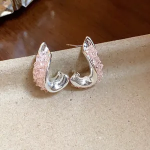 Detailed view of silver-tone irregular twisted earrings with sparkly pink glass accents