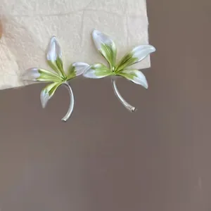 Vista dettagliata di eleganti orecchini a lobo a fiore in smalto verde e bianco.