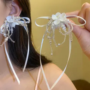 Detailed close-up of an elegant white floral tassel accessory with pearls and ribbons