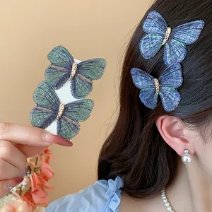 Detailed close-up showing two exquisite blue embroidered butterfly hair clips on dark hair