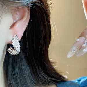 Close-up of elegant twisted silver earrings with sparkling glass stones on model
