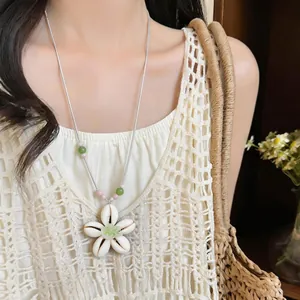 Dettaglio ravvicinato del ciondolo a fiore in resina e delle perle su una collana