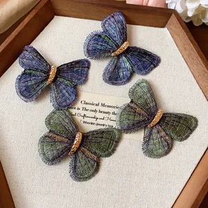 Close-up of elegant embroidered butterfly hair clips in blue and green tones