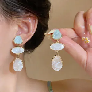 Detailed close-up showing elegant gold-framed resin teardrop earrings on a model's ear