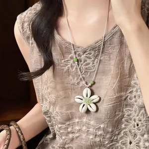 Dettaglio di una collana estiva con fiori in resina e perle indossata da una modella