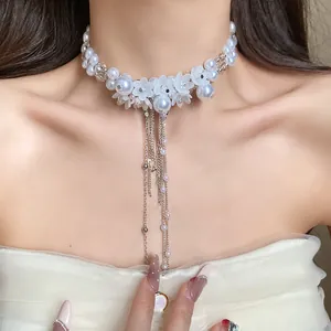 Close-up of elegant white pearl choker necklace with acrylic flowers and long chain tassels