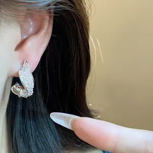 Close-up detail of twisted silver stud earrings with sparkling glass stones on ear