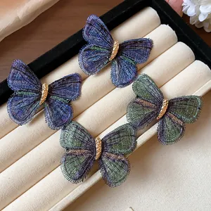 Detailed macro view of elegant embroidered butterfly hair clips on a velvet tray