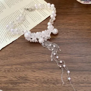 Elegant white pearl beaded necklace with frosted flower charms and silver tassels.