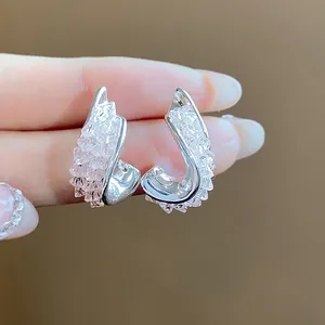 Macro detail showing the texture of twisted irregular silver earrings with faceted glass crystals.