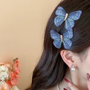 Detailed view of blue embroidered butterfly hair clips styled on model's wavy hair