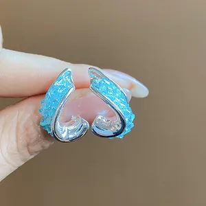 Macro detail shot of elegant twisted silver earrings with bright blue crushed glass inlay