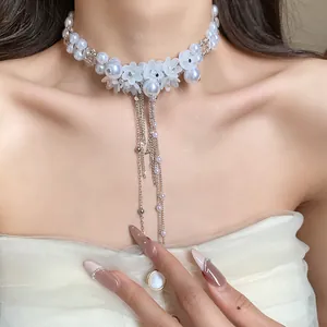 Close-up of white pearl floral choker necklace with elegant silver tassel details