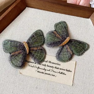 Detailed macro view of elegant green embroidered butterfly hair clips with golden accents