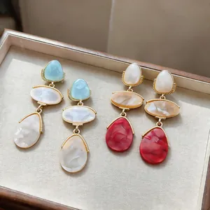 Detail view of colorful resin drop earrings with marble texture on jewelry tray